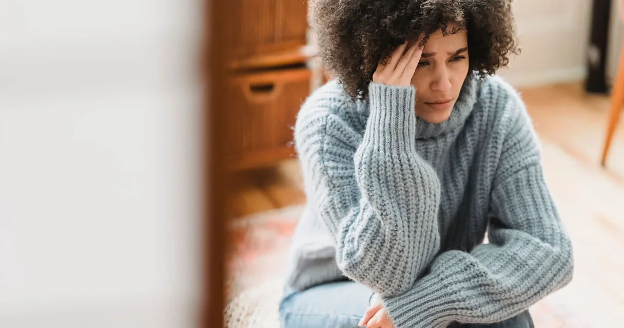 Mulher com expressão de dor sentada em casa